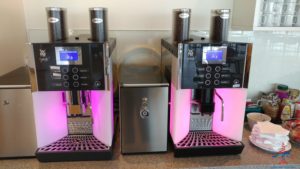 a group of coffee machines with pink lights