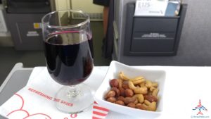 a glass of wine next to a bowl of nuts