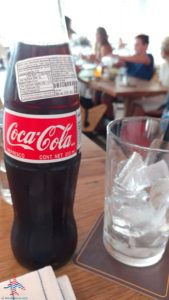 a bottle of soda next to a glass of ice