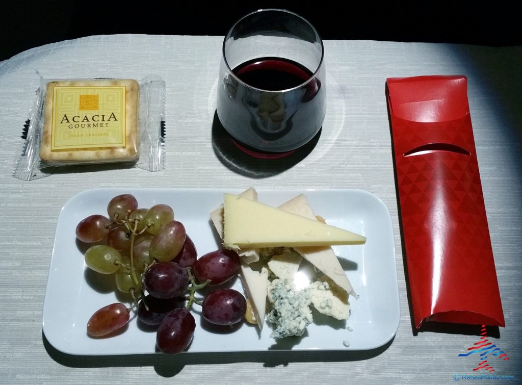 a plate of cheese grapes and a glass of wine