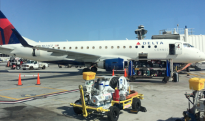 a white airplane with a cart on the tarmac