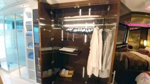 a closet with white coats on a swinger