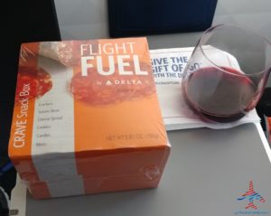 a box of food next to a glass of wine