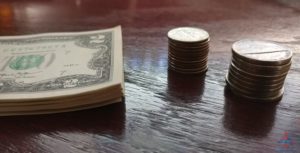 a stack of coins and a dollar bill on a table