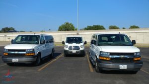 a group of white vans parked in a parking lot