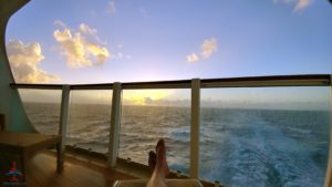 a person's legs on a deck overlooking the ocean