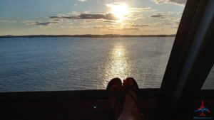 a person's feet in sandals overlooking a body of water