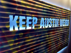 A piece of painted metal artwork with "Keep Austin Weird" emblazoned on it is displayed at the Delta Sky Club Austin airport lounge at Austin-Bergstrom International Airport (AUS) in Austin, Texas. Photo © Chris Carley / PointsLounge