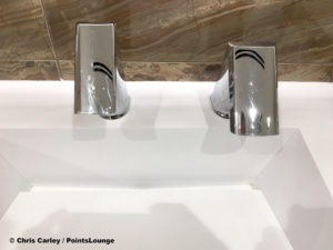 A sink, faucet, and motion activated hand dryer are seen inside the men's restroom at the Delta Sky Club Austin airport lounge at Austin-Bergstrom International Airport (AUS) in Austin, Texas. Photo © Chris Carley / PointsLounge