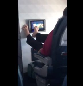 A Delta Air Lines first class passenger uses his feet on a screen.