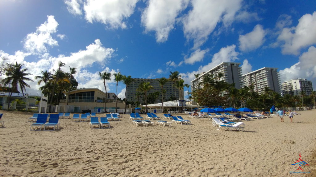 a beach with blue chairs and umbrellas