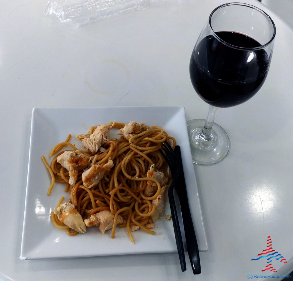 a plate of noodles and a glass of wine