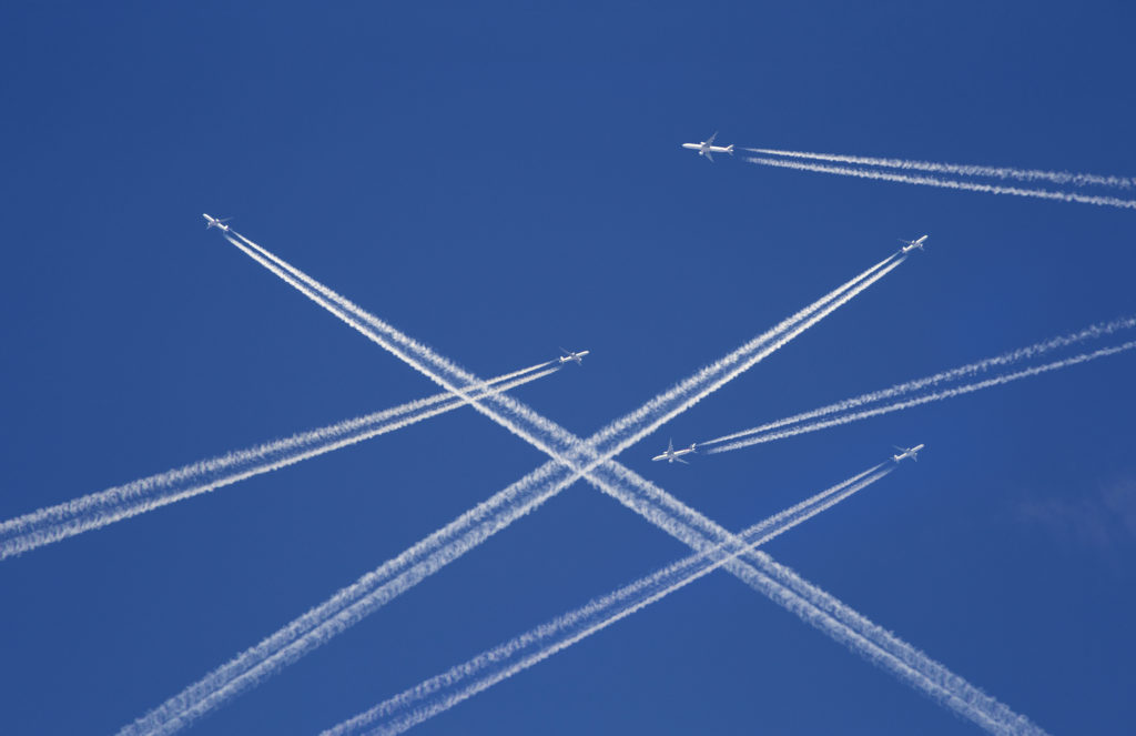 A lot of passenger airplanes on the air, busy air traffic, traveling high season starts concept. White planes against blue sky. Photo manipulation.