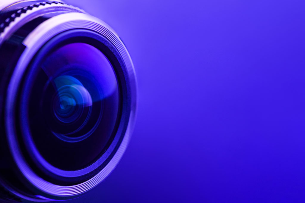 Camera lens with purple backlight. Side view of the lens of camera on purple background. Purple camera Lens close Up.
