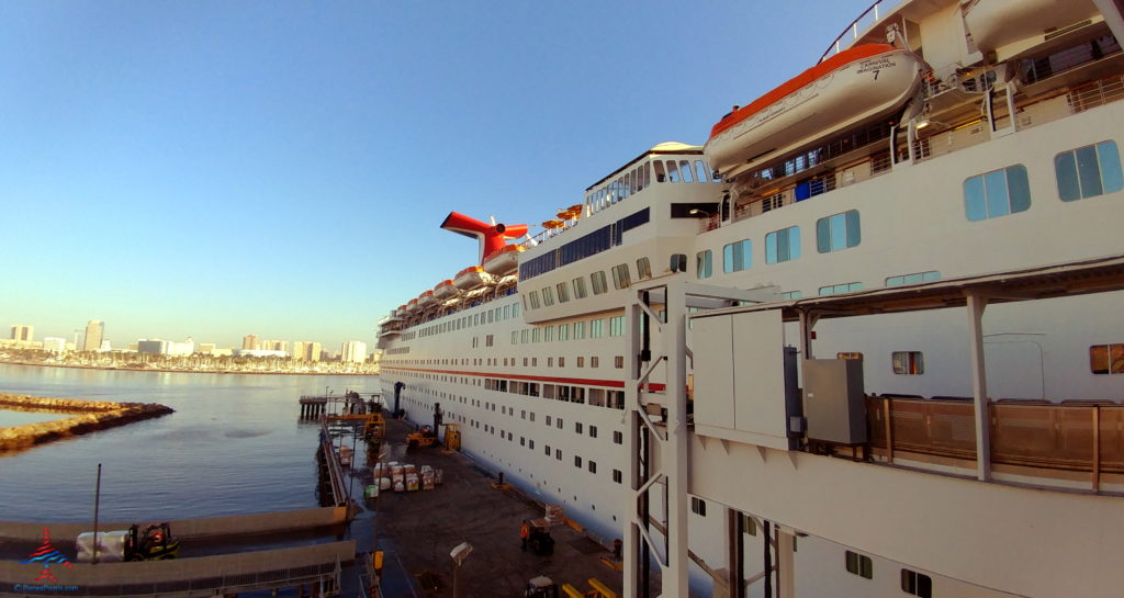 a large white ship with a red and white plane on the deck