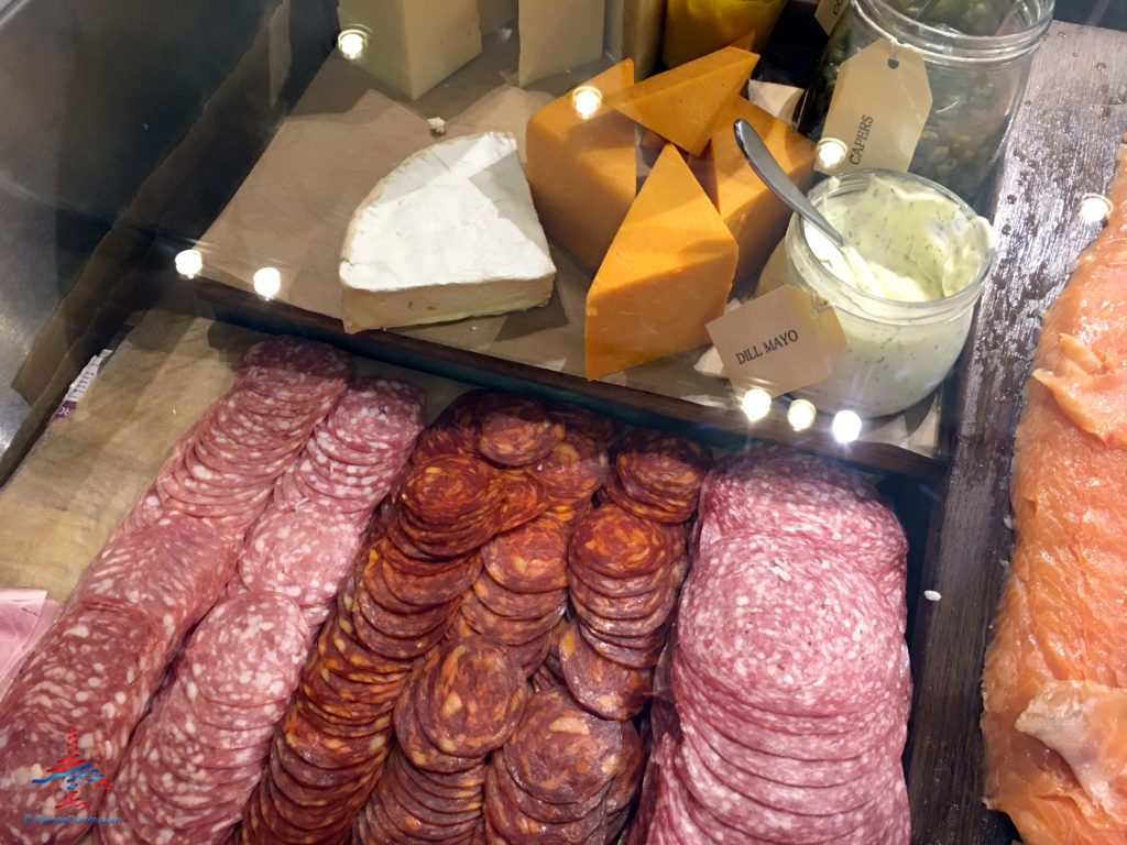 Charcuterie meats, assorted cheeses, and salmon/lox are seen inside the Virgin Atlantic Clubhouse airport lounge at London Heathrow Airport (LHR).