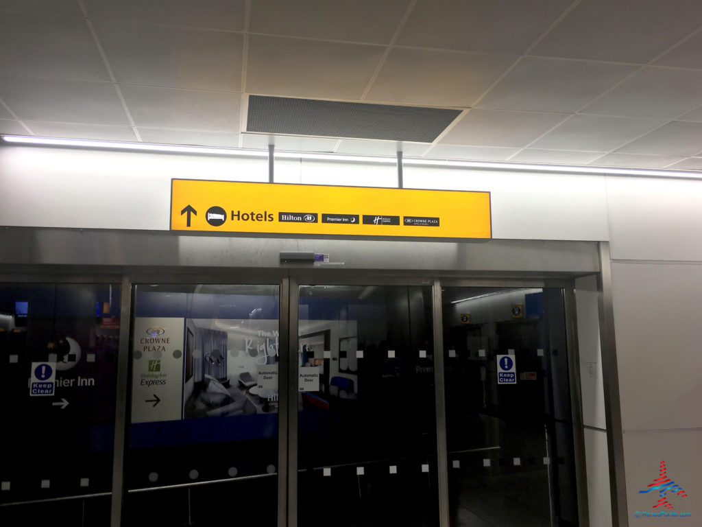 Signage inside Terminal 4 at Heathrow Airport directs guests to the Crowne Plaza, Holiday Inn Express, Hilton, and Premier Inn LHR hotels in Hounslow, United Kingdom.