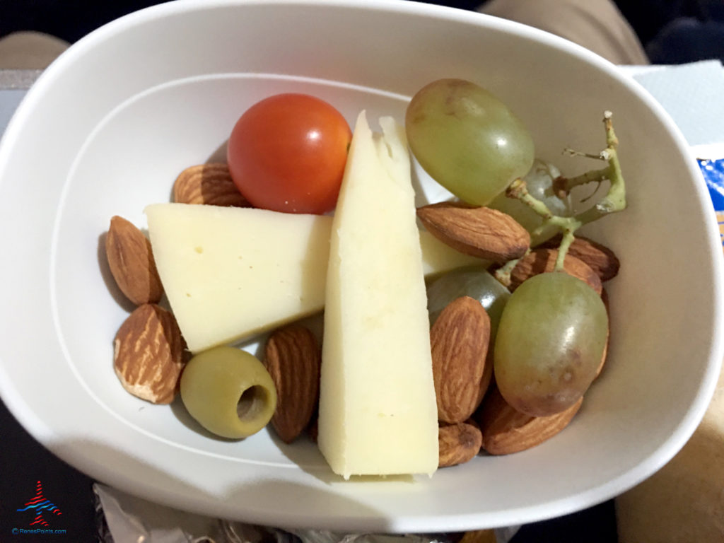 A fruit and cheese appetizer with almonds is featured as part of Delta's Main Cabin international experience as seen on a Delta Air Lines Airbus A330-300 flight from London Heathrow to Atlanta Hartsfield Airport.