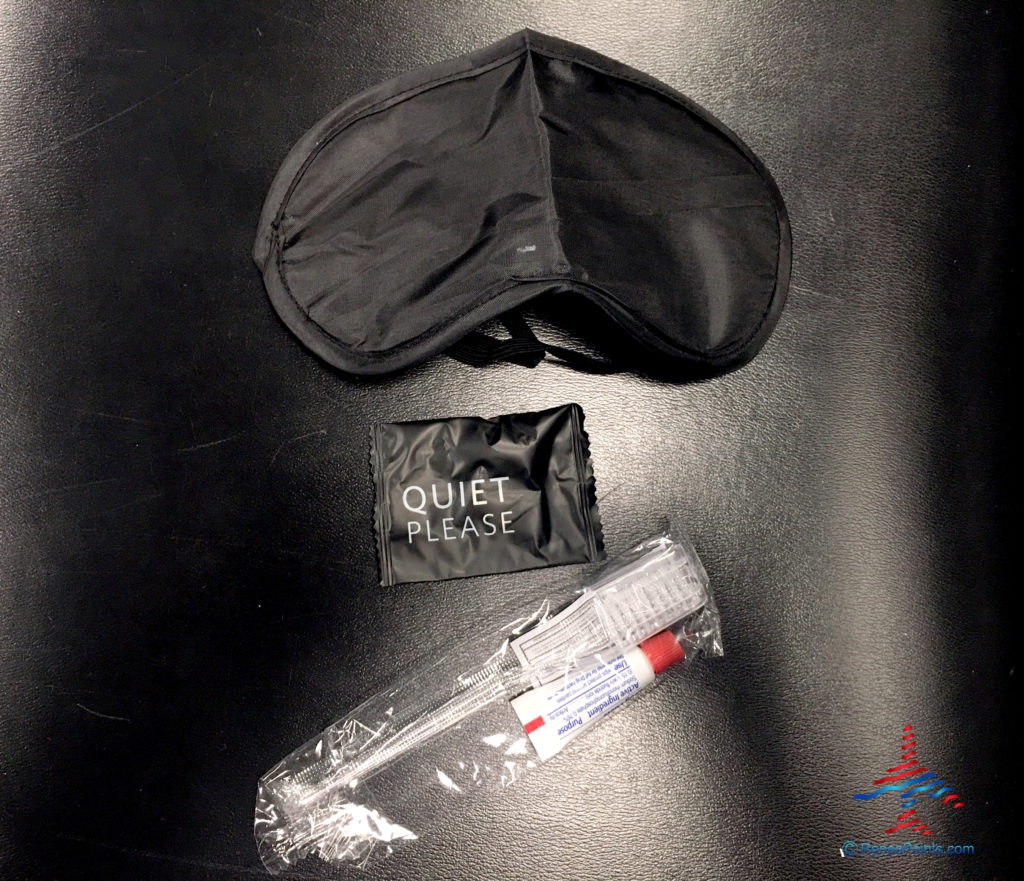 Ear plugs, a sleep mask, and toothbrush with tooth paste from a Sleep Kit offered in Comfort+ on Delta Main Cabin International Service.