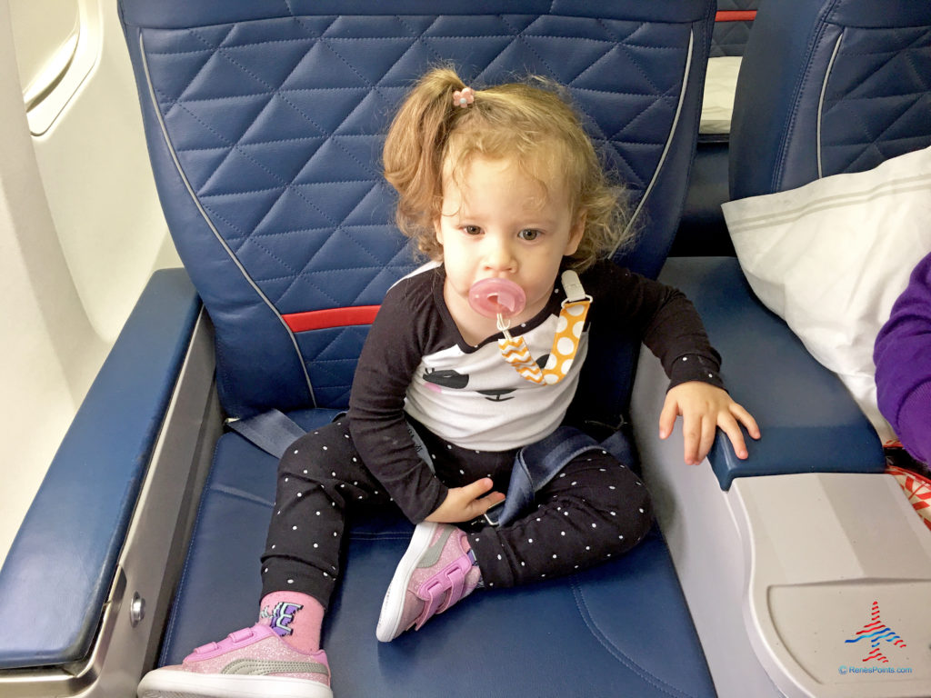 Writer Chris Carley's daughter sitting in first class on a Delta Air Lines flight, using the companion pass from one of his Delta American Express cards.