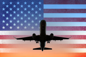 Airplane on sunset sky with American flag - USA travel concept. (Photo: ©iStock.com/hanohiki)