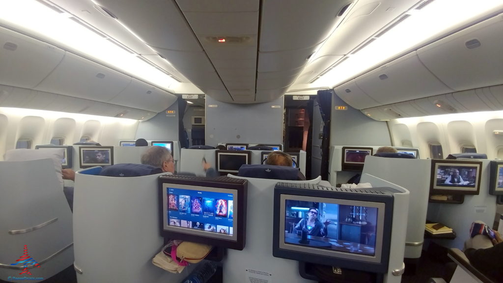 people sitting in an airplane with a few monitors