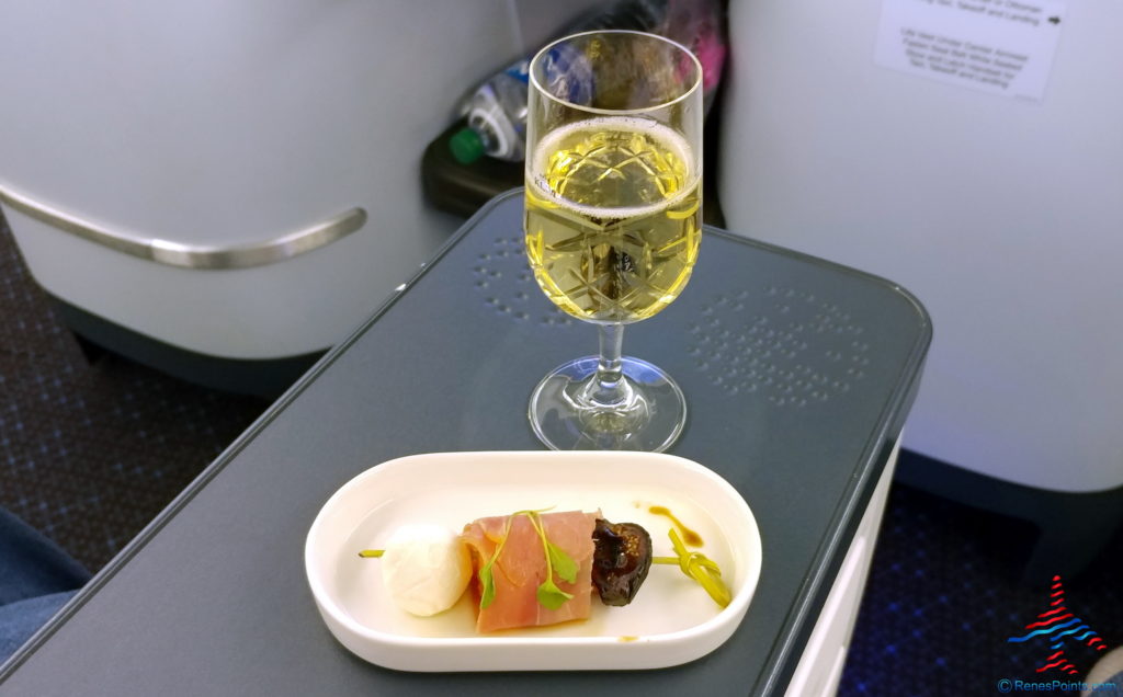a glass of wine and food on a tray