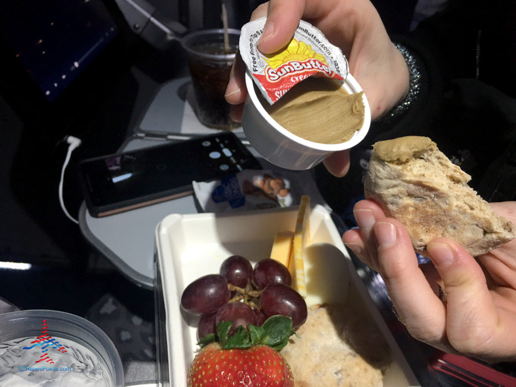 A whole grain museli snack round is dipped into sunflower seed butter from the Delta Air Lines Flight Fuel Protein Box premium snack.