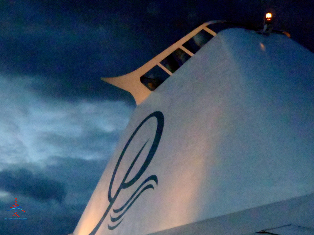 The Paul Gauguin Cruises logo is seen on their ship's stack at sunset.