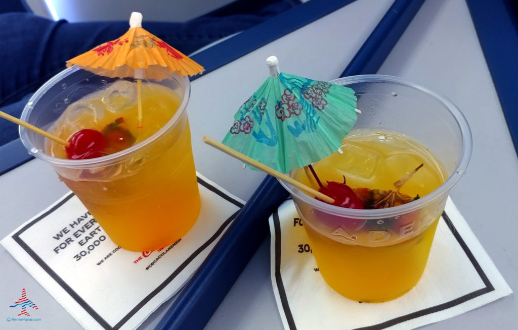 two cups of orange liquid with umbrellas