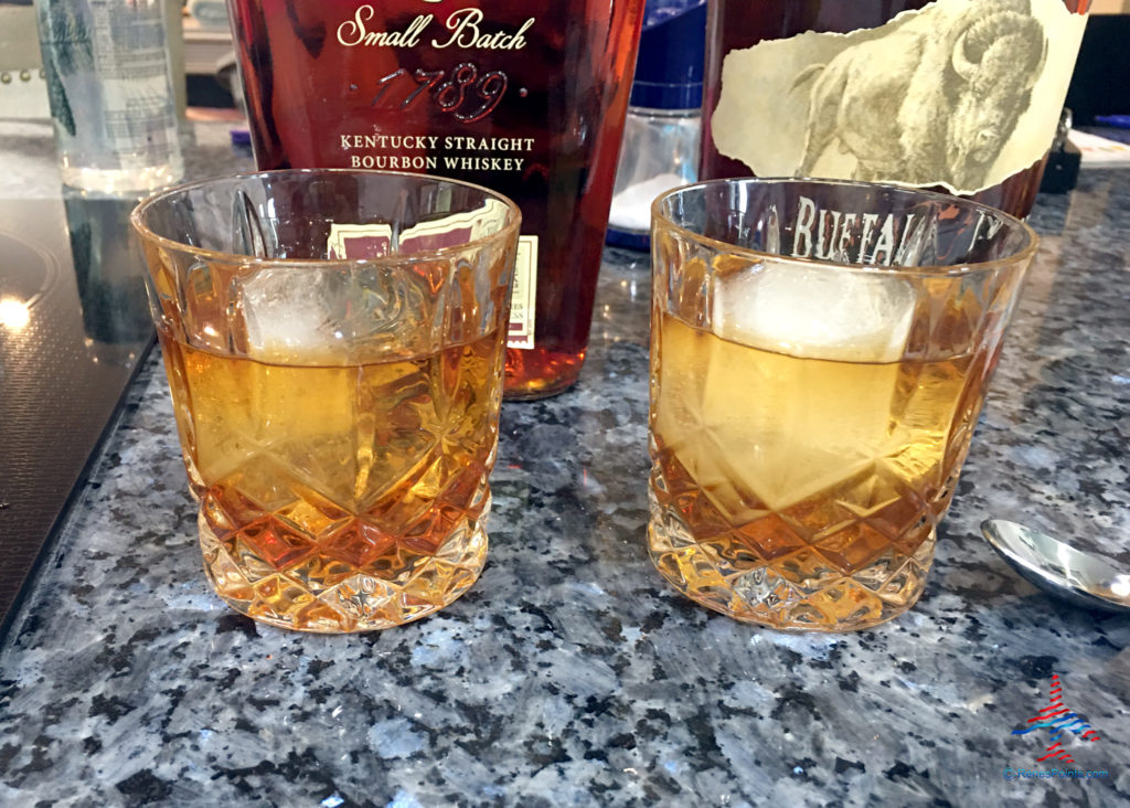 Bourbon whiskeys in double old fashioned glasses with large ice cubes.